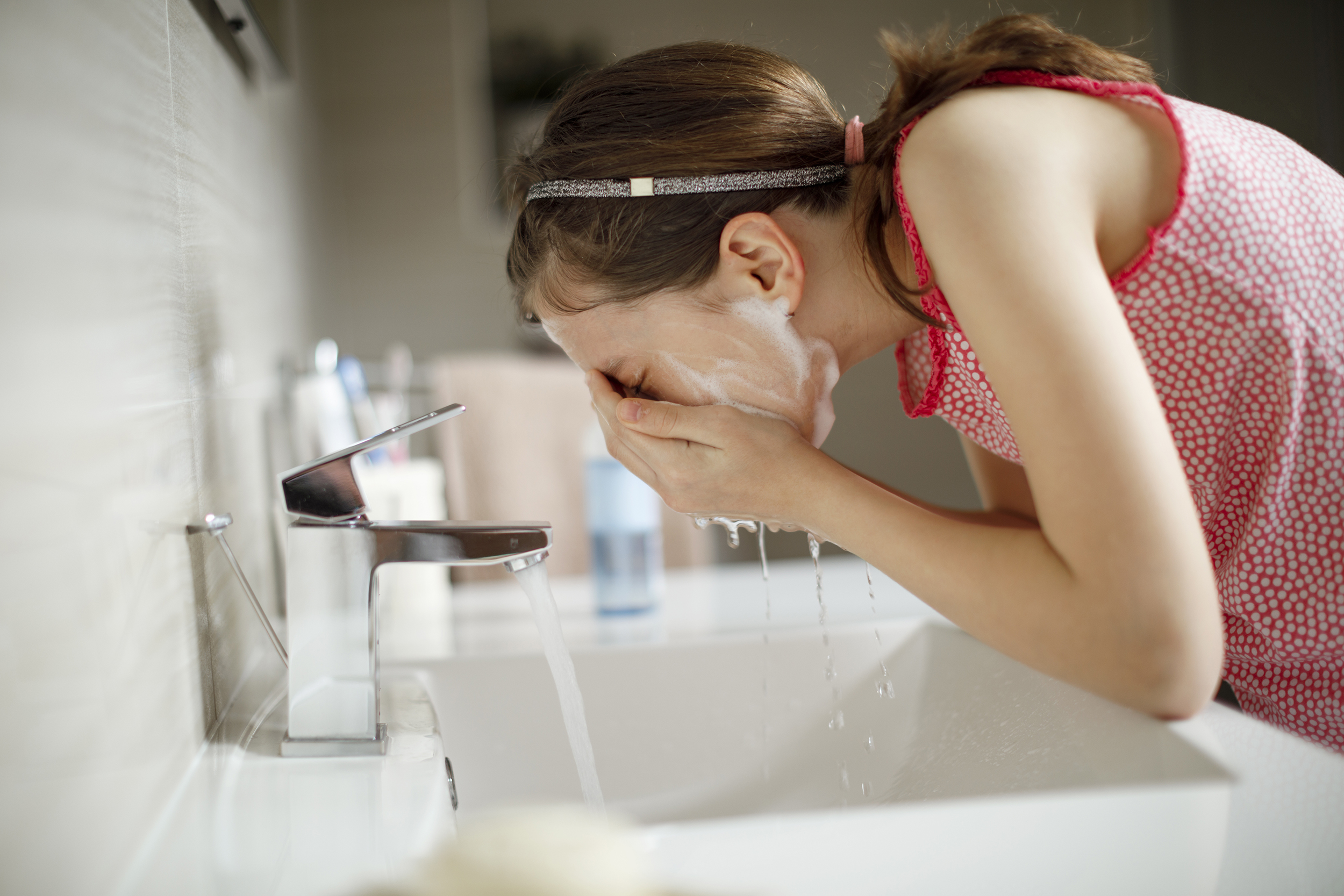 Adolescente lavando su cara para evitar acné